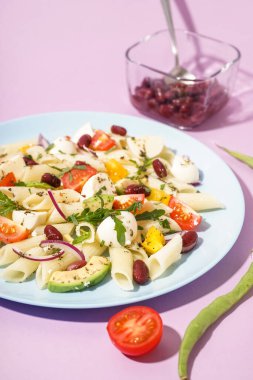 Lezzetli makarna salatası, domatesli ve arkaplanlı fasulye.