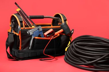 Alet çantası ve yuvarlanan esnek kanal tüpü kırmızı arkaplanda