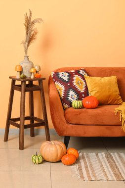 Oturma odasının içinde turuncu kanepe, dışkı ve farklı balkabakları var.