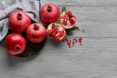 Taze olgun narlar ve gri ahşap arka planda tohumlarla dolu bir tabak.