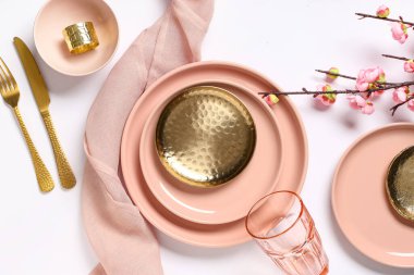 Altın çatal bıçak takımları ve gri arka planda çiçek açan dallarıyla güzel bir masa.