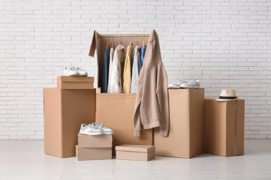 Giysileri ve ayakkabıları beyaz tuğla duvarın yanında.