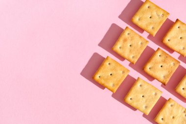 Pembe arka planda lezzetli krakerleri olan kompozisyon, yakın plan.