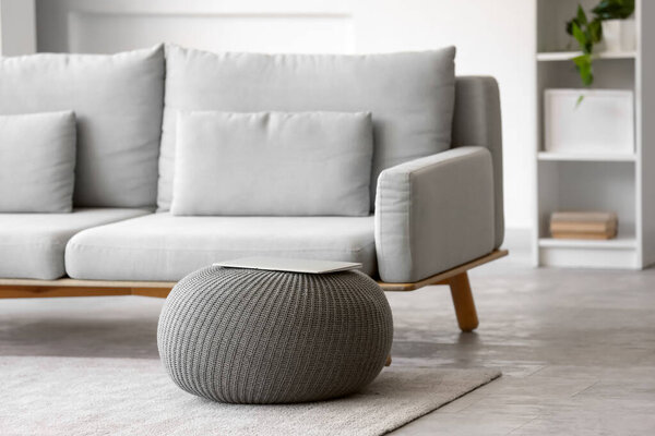 Laptop on grey pouf in living room interior