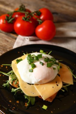 Ahşap arka planda lezzetli yumurta Benedict tabağı.