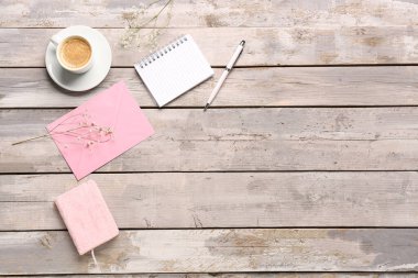 Kompozisyon defterleri, zarf ve bir fincan kahve yıpranmış ahşap masa üzerinde.