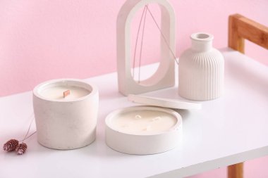 Odadaki pembe duvarın yanında elinde mumlar ve dekor olan tutucular, yakın plan.