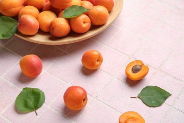 Pembe fayans masasında taze kayısı tabağı.