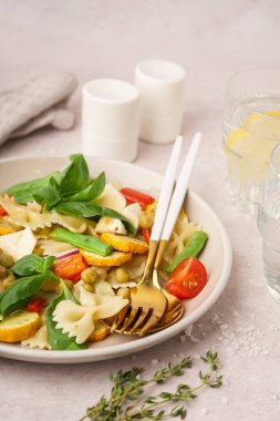 Beyaz arka planda bezelye ve fesleğenli lezzetli makarna salatası.