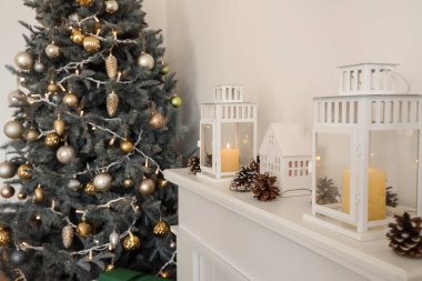 Ev şeklinde mum tutacağı olan fenerler ve Noel için dekore edilmiş şöminenin üzerindeki köknar konileri.