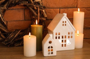 Ev şeklinde tutucuları olan mumlar yakmak ve tuğla duvarın yanındaki rafta Noel çelengi, yakın plan.