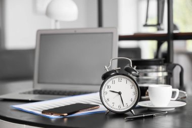 Ofisteki masada cep telefonu, kalem ve kahve dolu çalar saat.