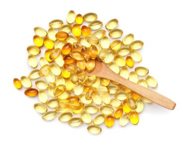 Beyaz zemin üzerinde E vitamini kapsülleri bulunan tahta kaşık.