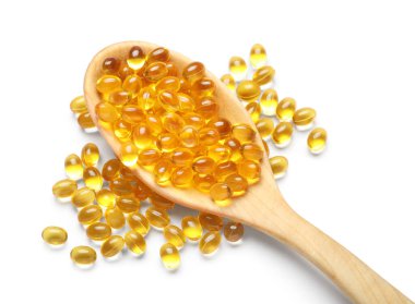 Beyaz zemin üzerinde E vitamini kapsülleri olan tahta kaşık.