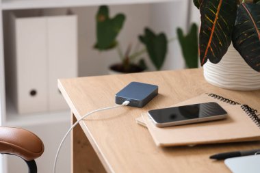 Çalışma masasında elektrik kablosu olan bir güç bankası, yakın plan.