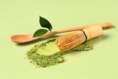 Yeşil arka planda chasen, kaşık ve taze yapraklı toz kibrit çayı.