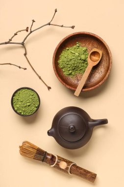 Bej arka planda pudralı kibrit çayı, chasen, kaşık, çaydanlık ve ağaç dalıyla kase