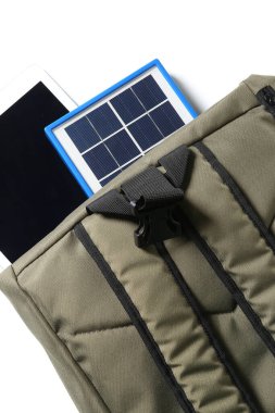 Backpack with portable solar panel and tablet computer on white background, closeup
