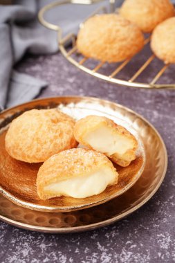 Arkaplanda lezzetli choux tatlılı tabaklar.