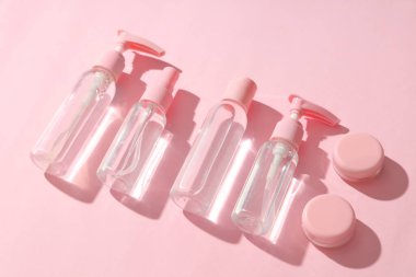 Pembe arka planda farklı seyahat kozmetik ürünleri.