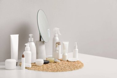 Işık duvarının yanındaki masada farklı kozmetik ürünleri ve ayna var.