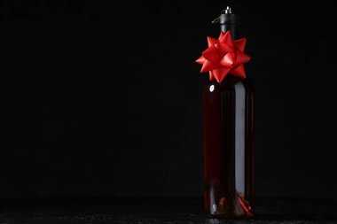 Siyah arka planda Noel kurdelesi olan bir şişe şarap