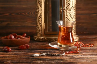 Bir bardak çay, dua boncukları, hurmalar ve ahşap masadaki Müslüman feneri. Ramazan kutlaması