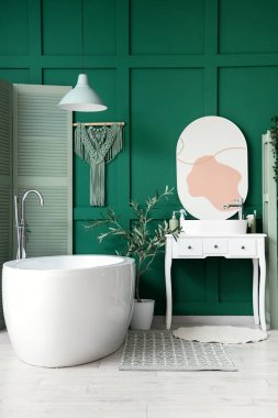 Banyonun içinde küvet, lavabo ve yeşil katlama ekran var.