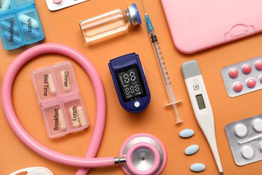 Bej arka planda nabız oksimetresi, steteskop, termometre ve ilaçlarla bileşim, yakın plan