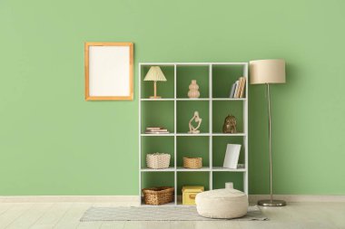 Yeşil duvarda puf, lamba ve boş posterle dizilin.
