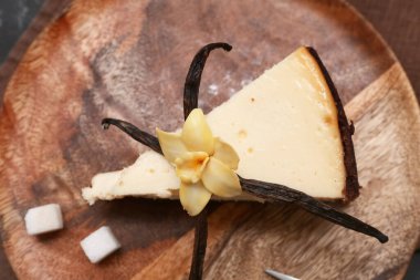 Siyah arka planda tatlı vanilyalı ahşap tabak ve şeker küpleri, yakın plan.