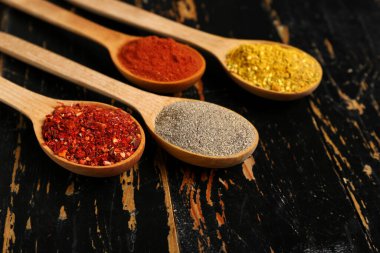 Koyu ahşap arka planda taze aromalı kaşıklar, yakın plan.