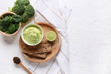 Limonlu, brokolili, ıspanaklı ve beyaz arka planda krakerli bezelye çorbası.