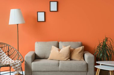 Rahat gri kanepesi, çiçekleri ve standart lambası olan şık bir oturma odası.