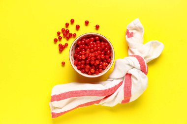 Sarı arka planda taze viburnum çilekleri olan bir kase.