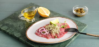 Lezzetli dana carpaccio, limon ve yağlı tabak.