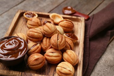 Ahşap arka planda kaynamış yoğunlaştırılmış sütle ceviz şekilli kurabiyeler kesme tahtası, yakın plan.