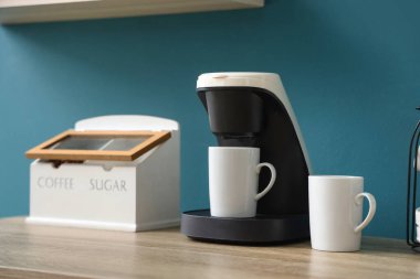 Kahve makinesi mavi duvarın yanındaki masada, yakın plan.