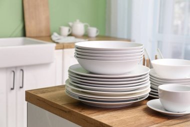 Mutfaktaki ahşap masada temiz beyaz tabaklar.