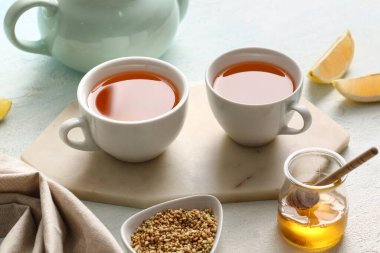 Bir fincan sıcak karabuğday çayı, bal ve limon dilimli kavanoz.