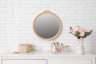 Beyaz tuğla duvarın yanındaki tuvalet masasında bir buket güzel ranunculus çiçeği olan vazo.