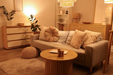 Rahat bir kanepe, oturma odasının içinde dizüstü bilgisayarı olan bir sehpa.