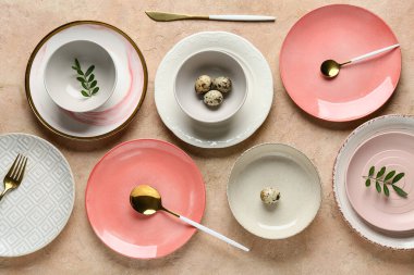 Farklı temiz tabaklar, bıldırcın yumurtaları ve bej arka planda taze yeşil yapraklar. Paskalya kutlaması