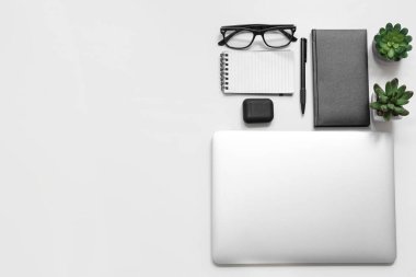 Kulaklık, not defteri ve beyaz arka planda gözlüklü dizüstü bilgisayar.