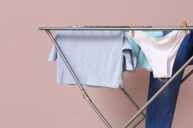 Pembe duvarın yanındaki kurutucuda asılı temiz kıyafetler.