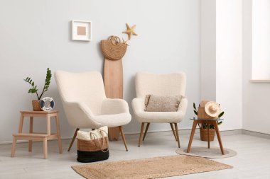 Beyaz koltuklu, el çantalı, sörf tahtalı ve yaz dekorlu şık bir oturma odası.