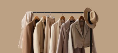 Şık kıyafetler ve bej arka planda şapkası olan raflar.