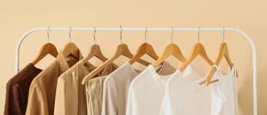 Bej duvarın yanında şık kıyafetler var.