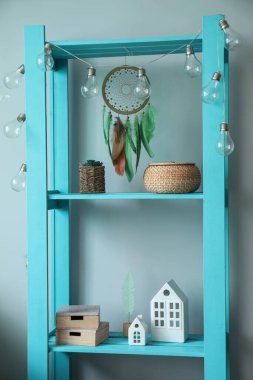 Renkli duvarın yanındaki raflarda asılı rüya yakalayıcı.