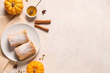 Beyaz arka planda lezzetli balkabaklı turta, tarçın, tohum ve bal dolu tabak.